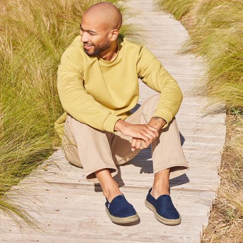 Mens Alpargata Rope Espadrille In Navy Recycled Cotton  On Model Sitting On Wooden Walkway