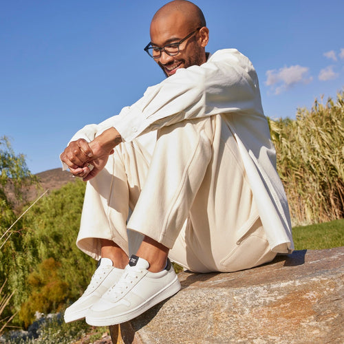 White Leather Court Sneaker On Model Sitting On Rock
