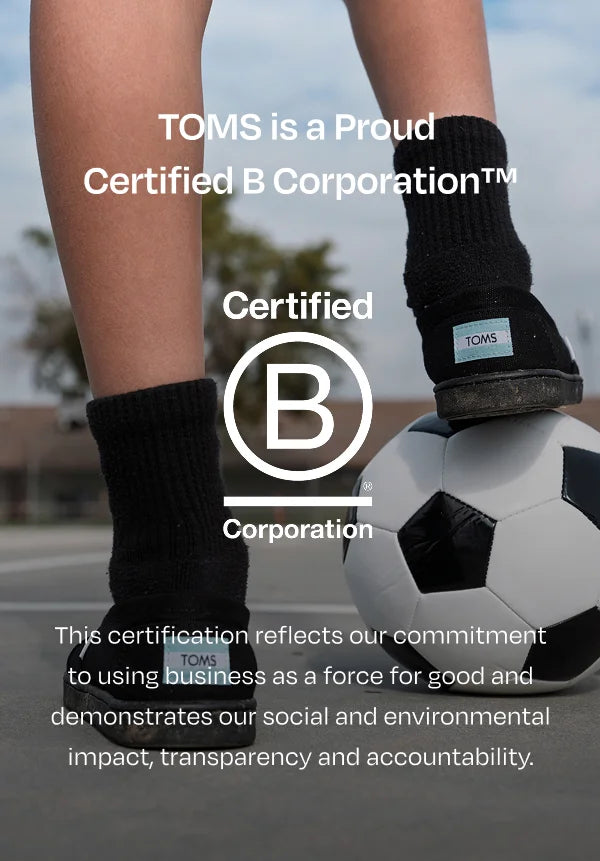 Bcorp logo. TOMS is proud to be a  Certified B Corporation™. This certification reflects our commitment to using business as a force for good and demonstrates our social and environmental impact, transparency and accountability. Child resting foot on soccer ball.