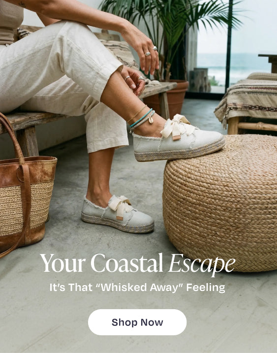 Your Coastal Escape. It's That "Whisked Away" Feeling. Shop Now: model wearing Carolina Lace-Up Espadrille in White Onyx Textured Denim, beach background.